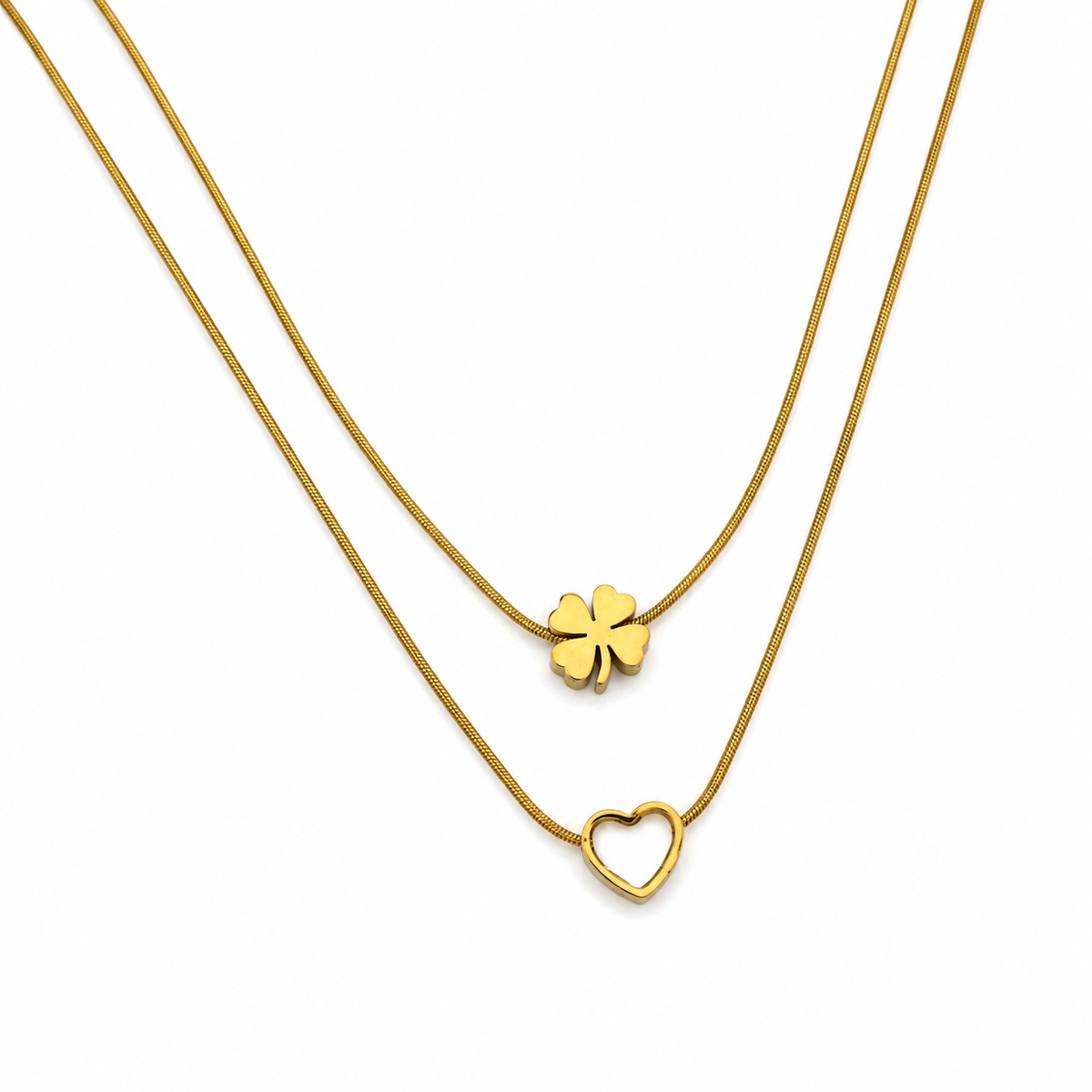 A double-strand gold necklace set featuring a delicate snake chain with a small four-leaf clover pendant and a slightly thicker chain with an open heart pendant, displayed on a clean white background.