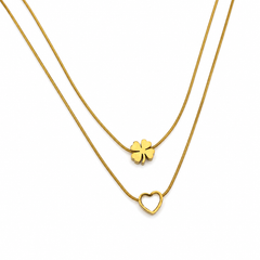A double-strand gold necklace set featuring a delicate snake chain with a small four-leaf clover pendant and a slightly thicker chain with an open heart pendant, displayed on a clean white background.