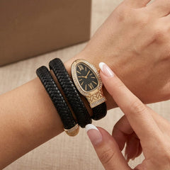 A close-up of a woman's wrist wearing a multi-strand black leather bracelet watch with a gold-tone oval case and a black dial, with her finger touching the watch face.