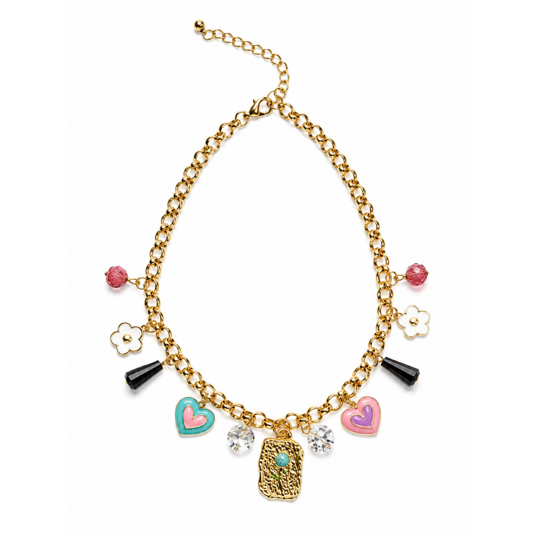 A gold-tone chain necklace with multiple dangling charms, including pink hearts, a turquoise and pink heart, a gold locket, white flower outlines, black cone charms, and clear rhinestones, shown on a plain white background.