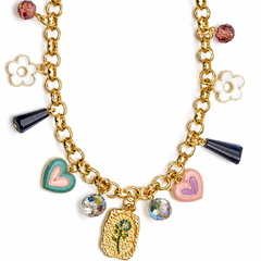 A gold-tone chain necklace with multiple charms, including two pink-and-green hearts, a pink-and-white flower, faceted crystal beads, dark blue teardrop beads, and a textured gold plaque with a small floral design.
