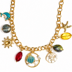 Gold-tone chain necklace with ocean-themed charms including a turquoise dolphin, seashell, starfish, sun, and faceted beads in red, yellow, and green, shown on a white background.