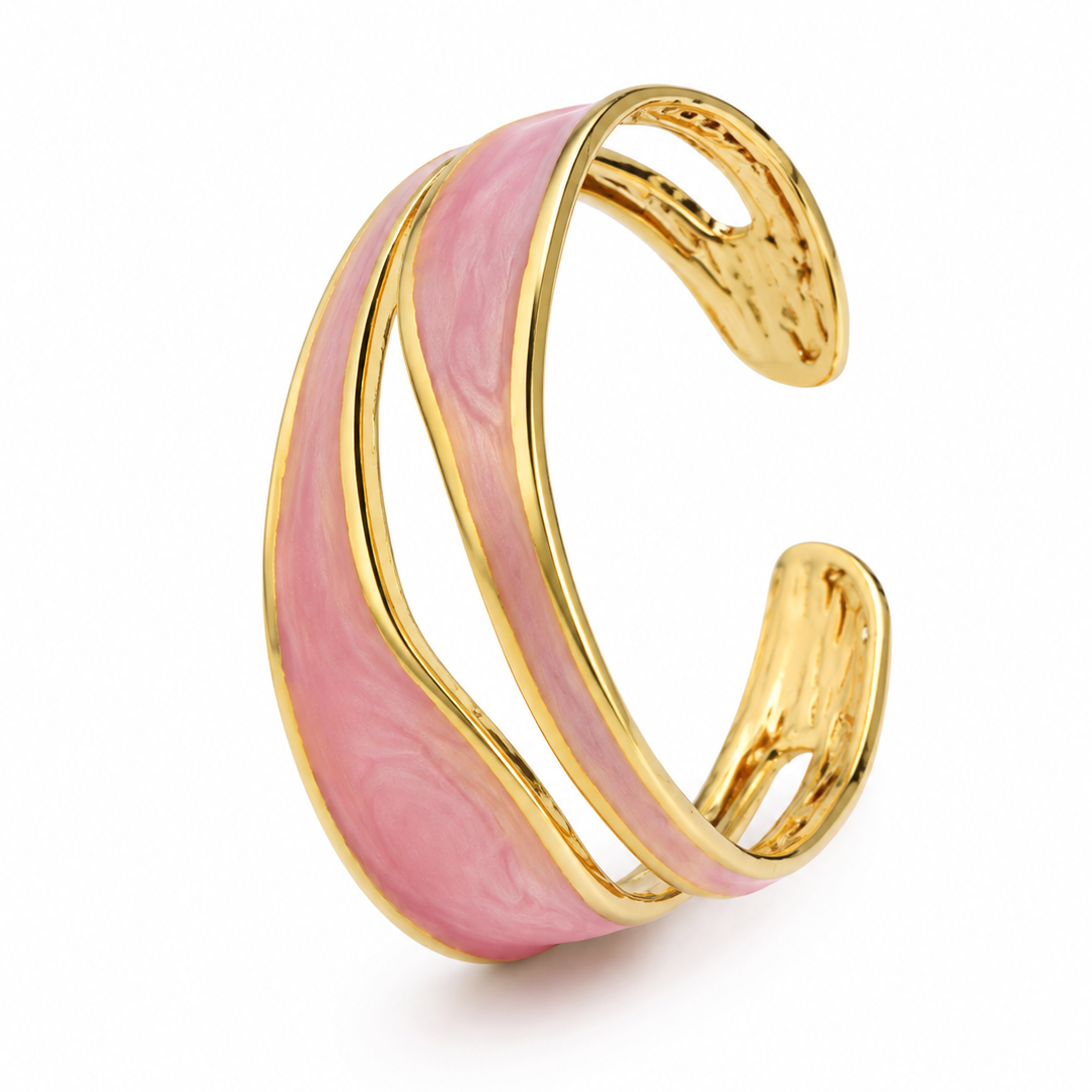 A gold-toned open cuff bracelet featuring a wavy, layered pink enamel inlay, shown on a clean white background.