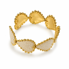 A gold-tone cuff bracelet featuring alternating smooth and textured oval segments, each bordered by small gold beads, shown on a clean white background.