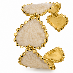 A gold-tone cuff bracelet featuring three large, textured cream-colored stone inlays with scalloped edges, set against a plain white background.
