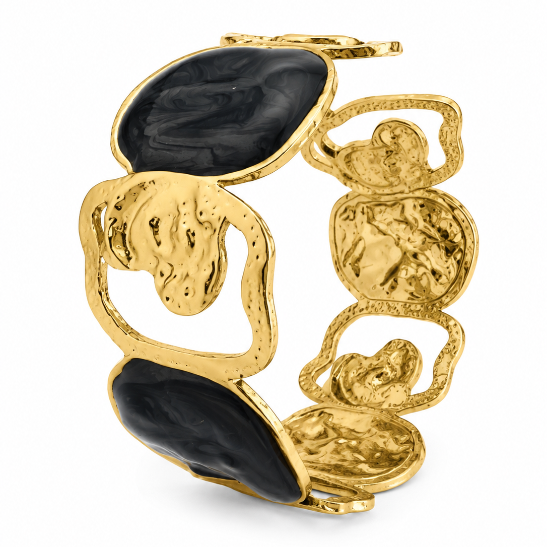 A gold-tone cuff bracelet featuring organic, sculptural openwork links and large polished black stone inlays, shown on a clean white background.