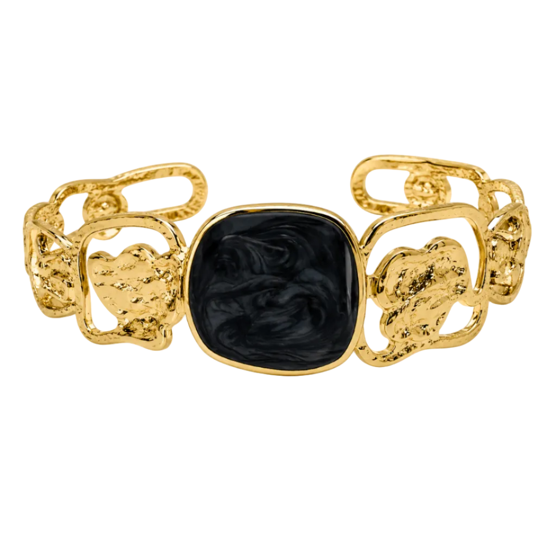 A gold-tone cuff bracelet featuring a central square black onyx inlay with swirling marbled patterns, flanked by textured gold heart-shaped links on a white background.