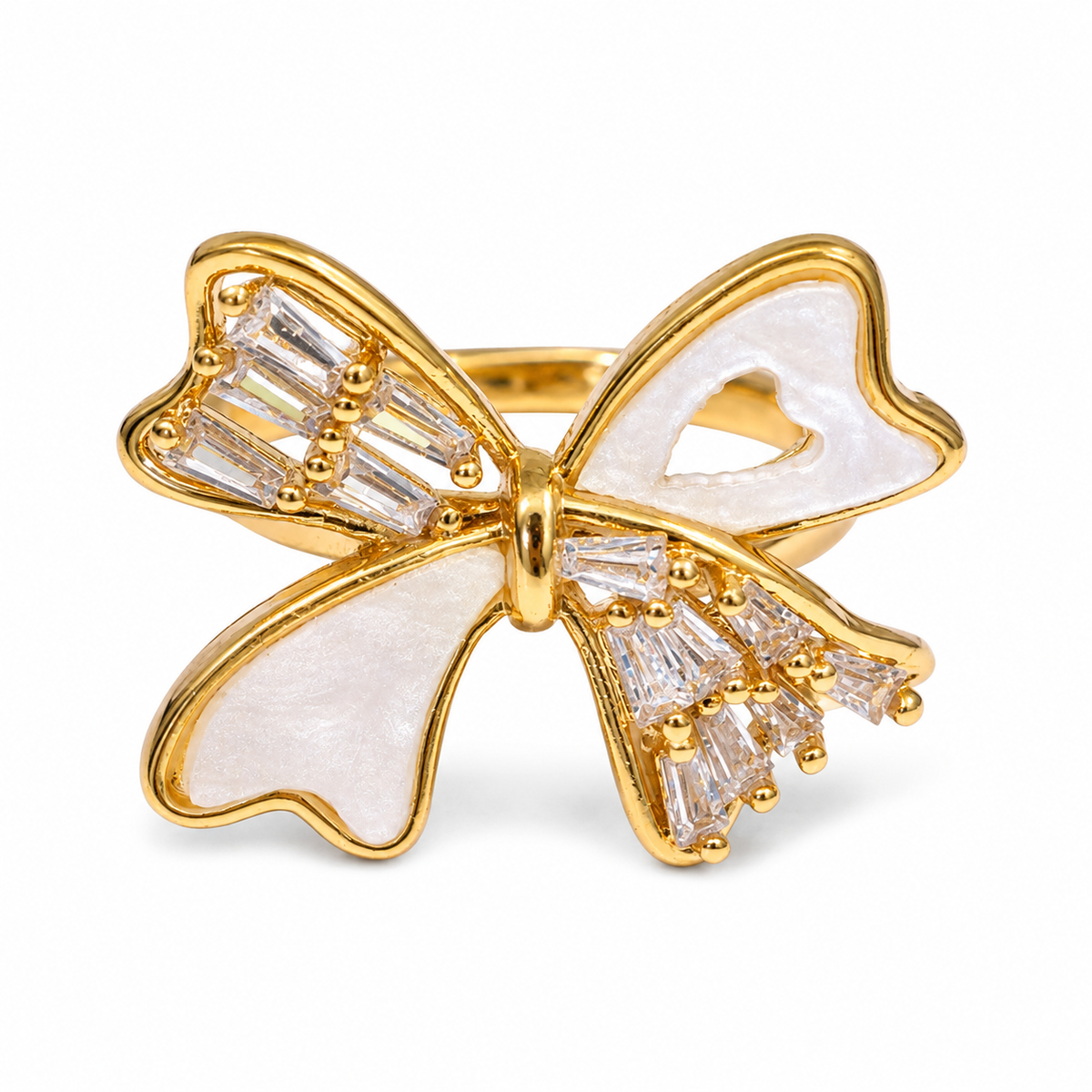 A gold bow-shaped ring featuring white mother-of-pearl inlays and clear baguette crystals, shown on a clean white background.