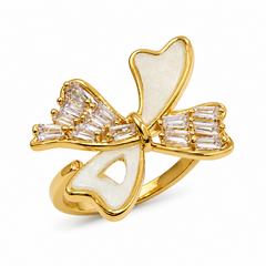 A gold ring shaped like a bow, featuring smooth white enamel inlay and clear baguette-cut gemstones on the sides, shown on a clean white background.