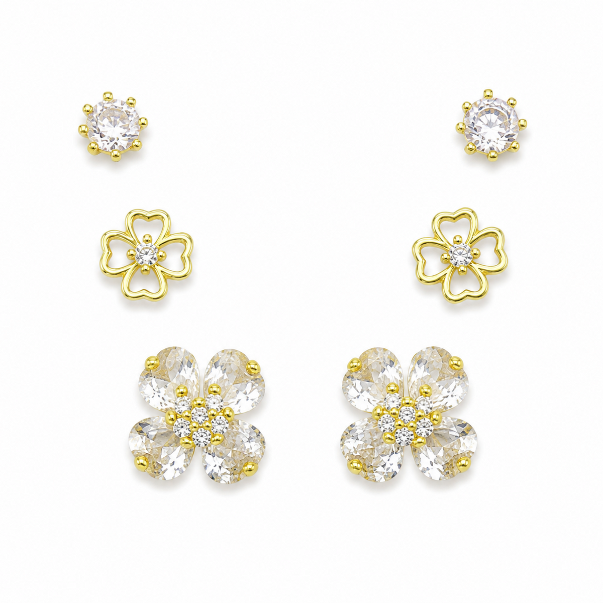 A set of gold and clear crystal flower-shaped stud earrings arranged on a plain white background, including smaller round and larger petal clusters.