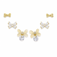 A set of five gold-tone stud earrings arranged on a white background, including two bow-shaped earrings, two butterfly-shaped earrings with clear rhinestones, and two flower-shaped earrings with pale yellow petals and clear rhinestones.