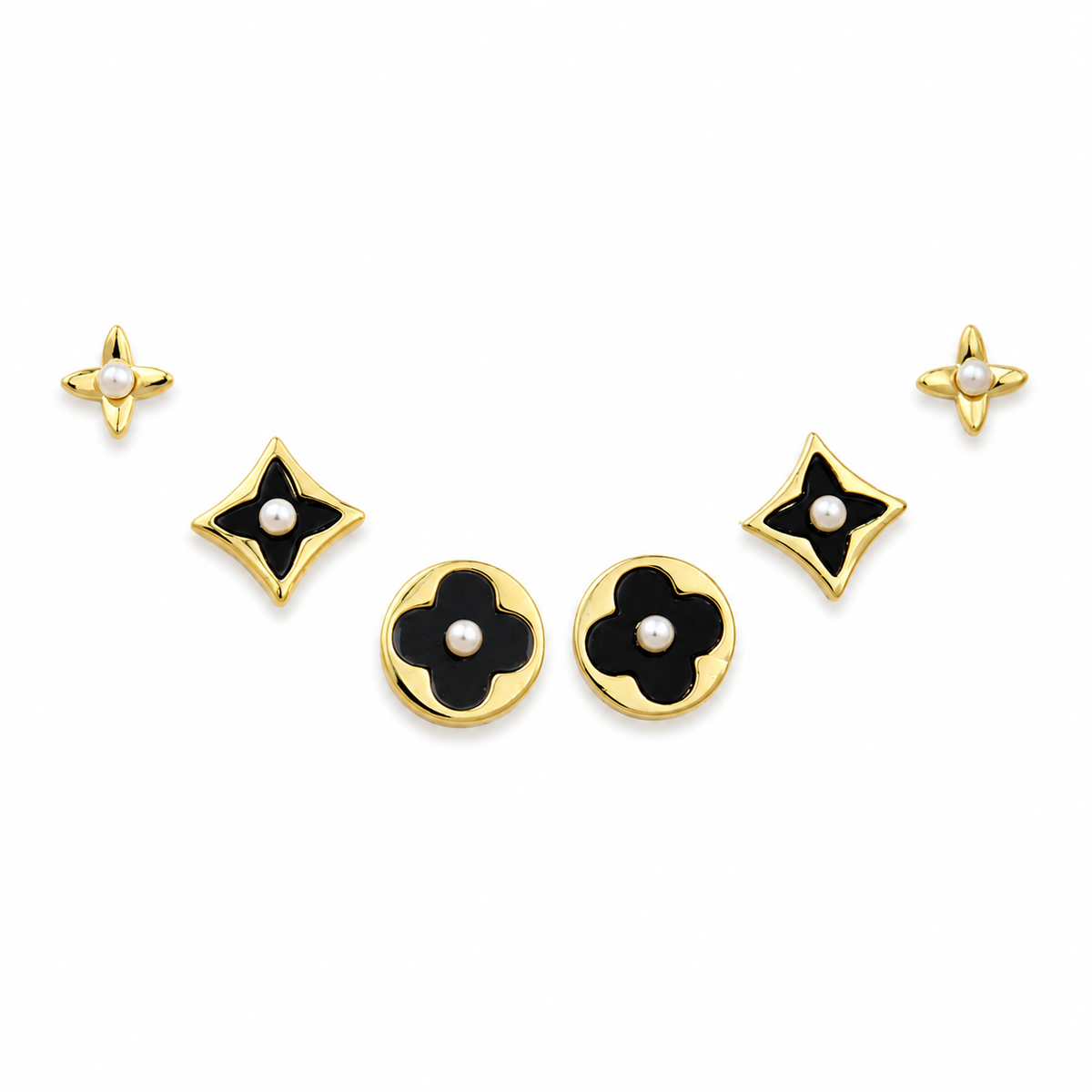 A set of five gold-tone jewelry pieces with black enamel floral and star motifs, each accented with a small white pearl, arranged on a plain white background.