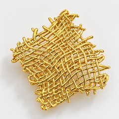 A gold-colored abstract wire mesh or woven net design, photographed on a clean white background.