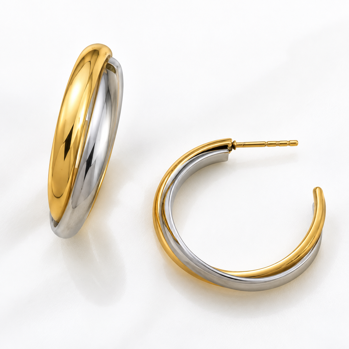 Two two-tone hoop earrings in polished yellow gold and silver, displayed on a clean white background.