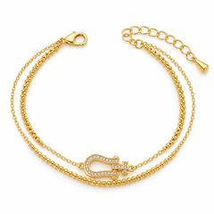 A gold double-layered chain anklet featuring a central horseshoe-shaped charm embellished with clear rhinestones, shown on a clean white background.