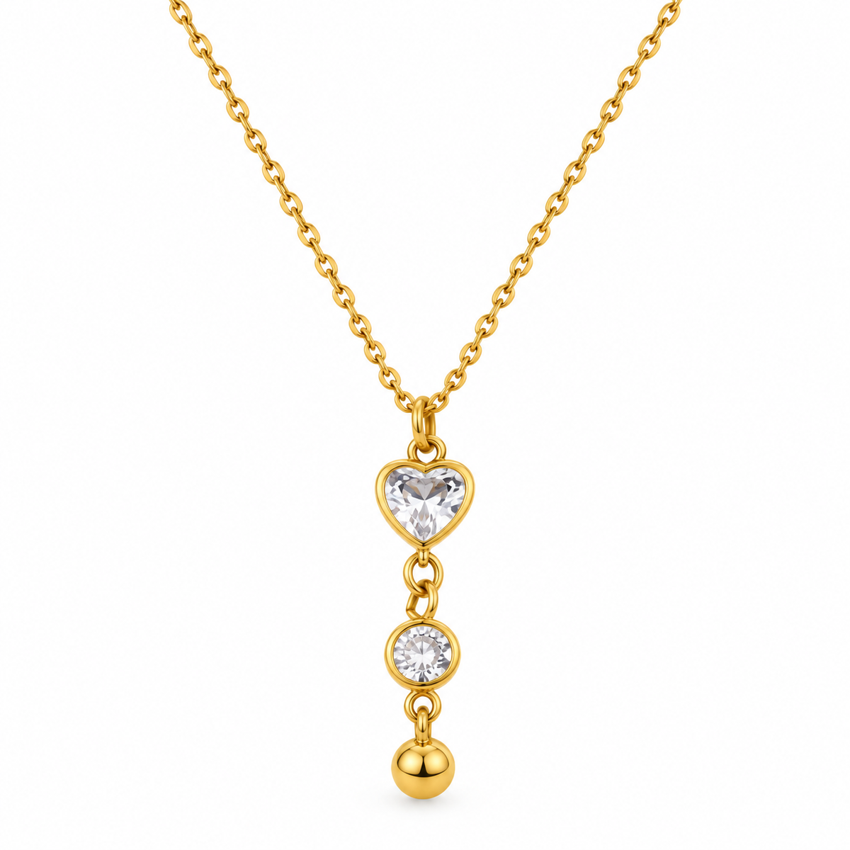 A gold necklace with a heart-shaped clear gemstone pendant, a round clear gemstone, and a small gold bead dangling below, shown on a plain white background.