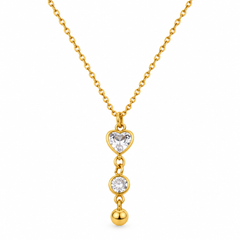 A gold necklace with a heart-shaped clear gemstone pendant, a round clear gemstone, and a small gold bead dangling below, shown on a plain white background.